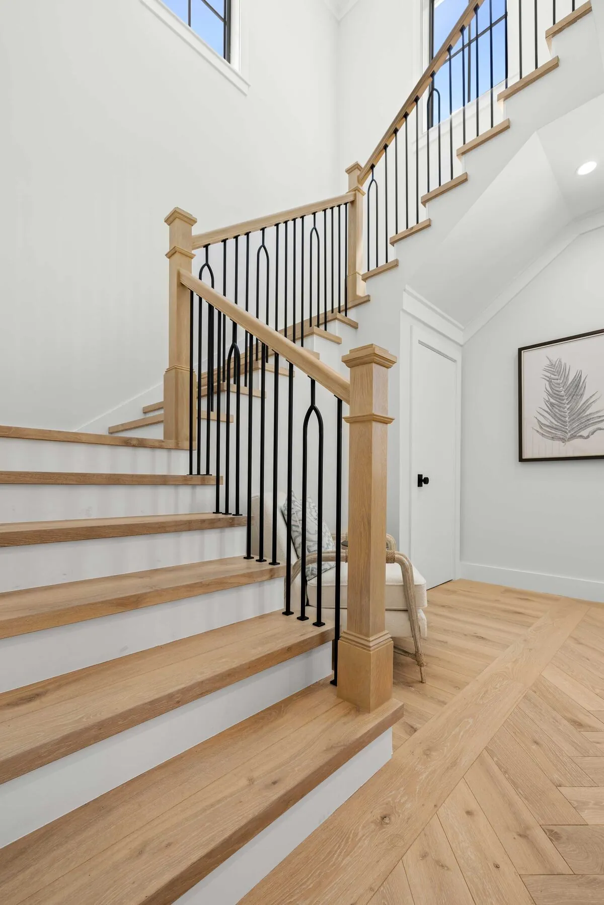 Oak staircase with iron balusters above a herringbone floor